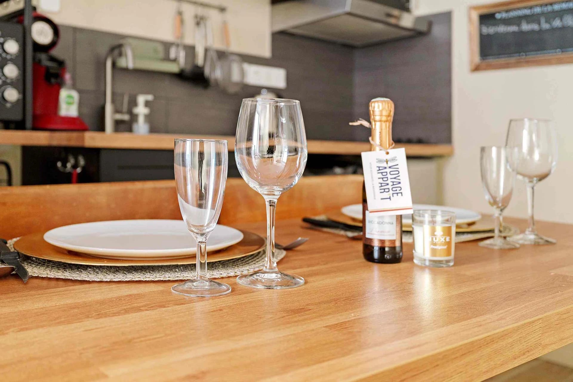 Table dressée avec verres, bougie et attention de bienvenue